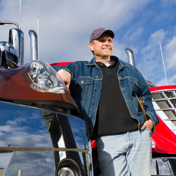 man standing beside two semi trucks